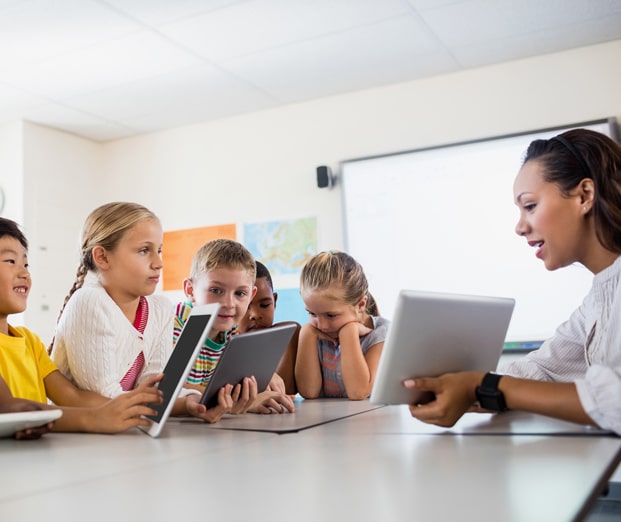 teacher and young students using tablets in a classroom