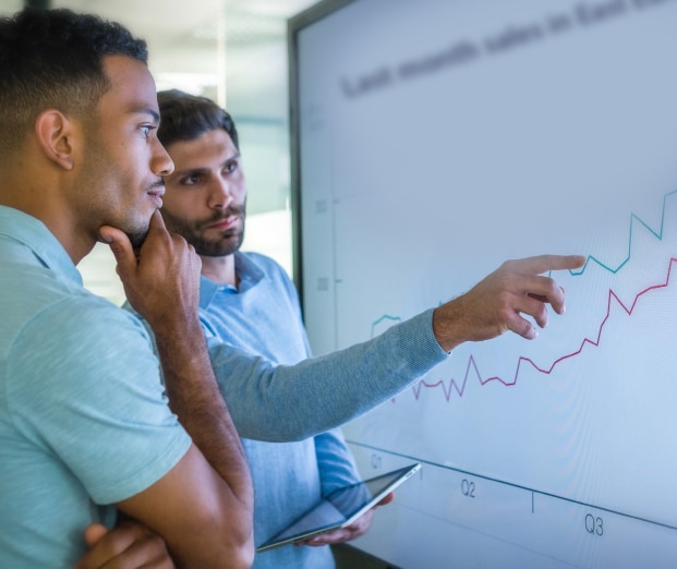 two men looking at data on a large screen
