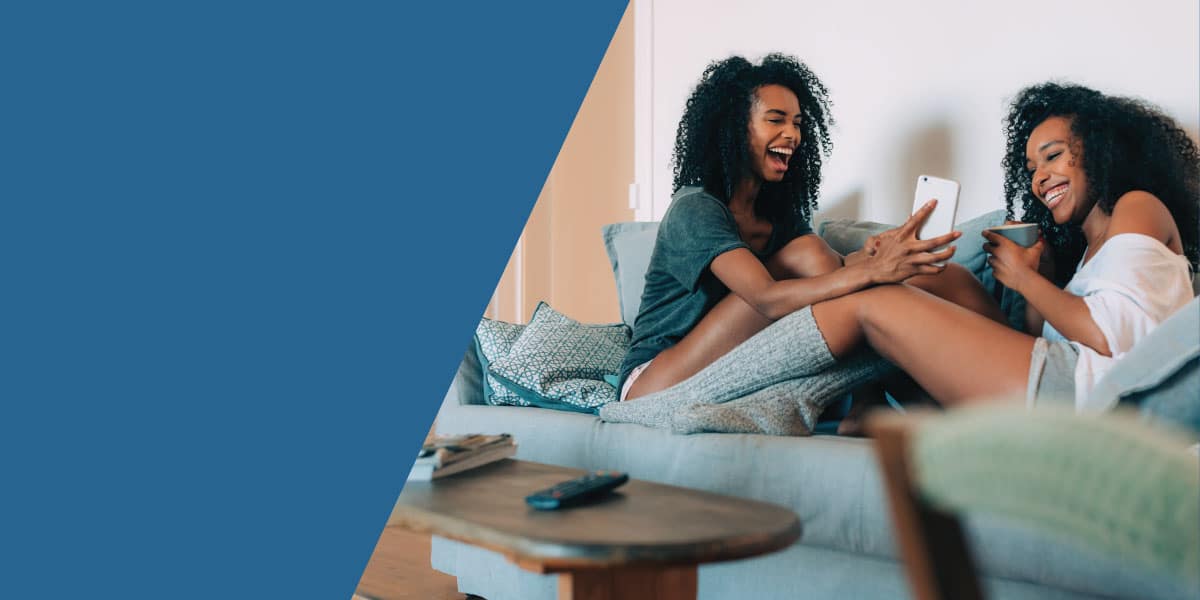 girls-on-couch-looking-at-smart-phone